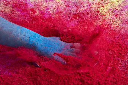 Close-up of hand splashing red powder paint during Holi festivalの写真素材