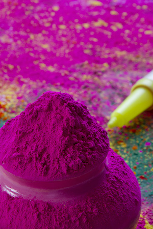 Close-up of pink Holi color powder with water gun in backgroundの写真素材