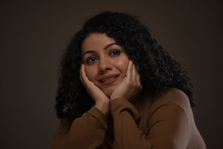 Close-up portrait of a woman with hands on cheek looking away and thinking