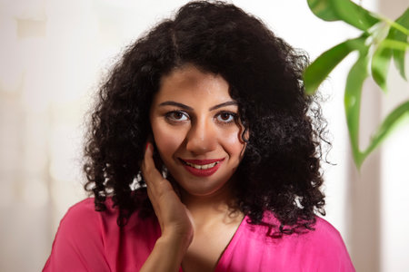 Close-up portrait of a beautiful woman looking at camera with hand on cheekの写真素材