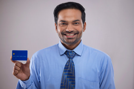 Portrait of a happy businessman showing credit card in front of camera with smileの写真素材