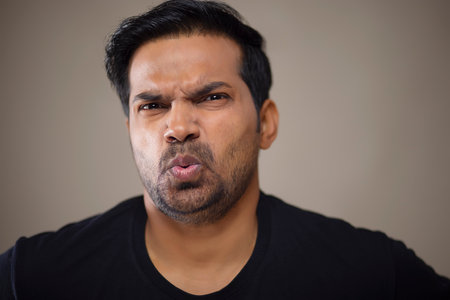 Close-up portrait of a disappointed young man against dark background