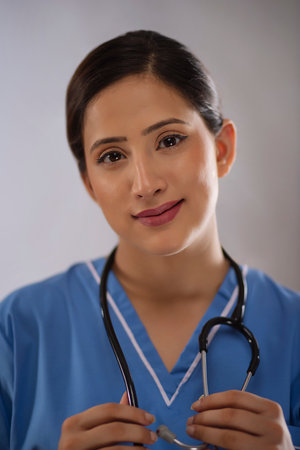 Close-up portrait of a young beautiful female nurse against plain backgroundの写真素材