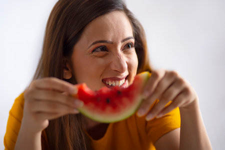 Young woman eating watermelon against white background