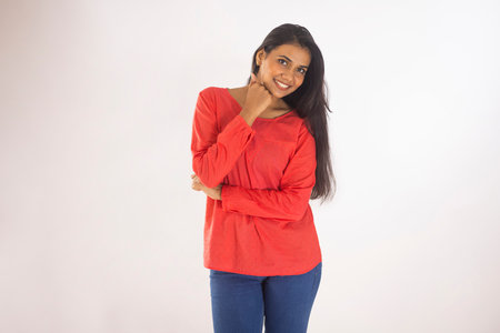 Portrait of a cheerful young woman standing against white backgroundの写真素材