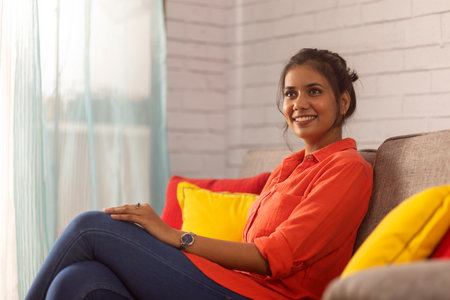 Portrait of a cheerful woman relaxing on sofa in living room