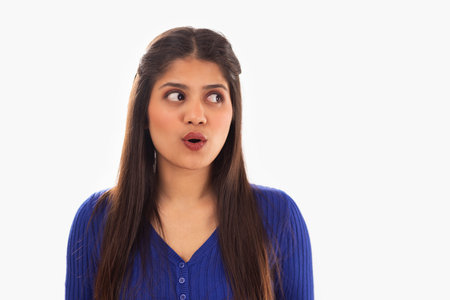 Portrait of beautiful woman gesturing against white backgroundの写真素材