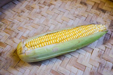 Close up of raw sweet corn with wooden background. Raw corn ready to be cooked.の写真素材