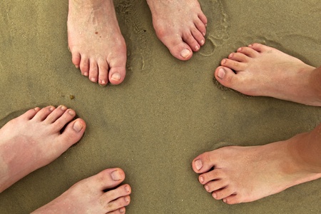 feet of family standing together at beach