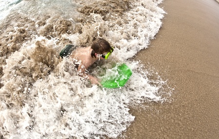 boy has fun with the surfboard at the beachの写真素材