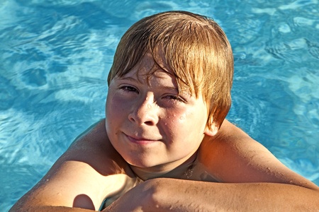 happy child rest on his elbow at the edge of the poolの写真素材