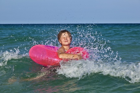 happy boy in a swim ring has fun in the ocean