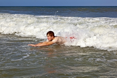 young boy is body surfing in the waves of the oceanの写真素材