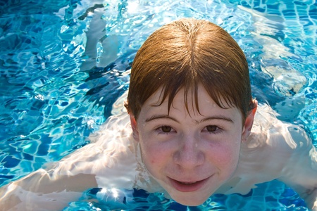boy with red hair is swimming in the pool and enyoing the fresh water boy with red hair is swimming in the pool and enyoing the fresh water