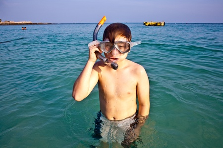 young boy is standing in the beautiful clear sea, enjoying the water and starts snorkelingの写真素材