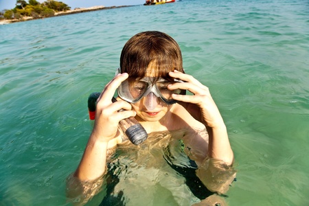 young boy likes to snorkel in the clear water at the beautiful beachの写真素材