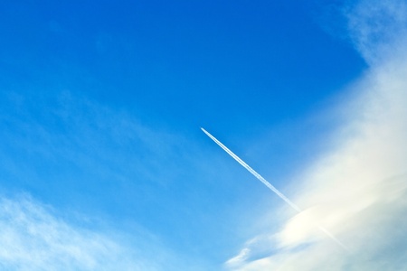 beautiful blue sky with condensation trail of an aircraftの写真素材