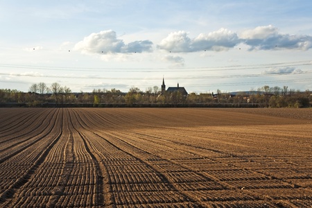 freshly ploughed acre in beautiful light with housing area at horizonの写真素材