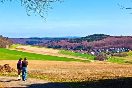 people watching the beautiful landscapelandscape with fields and a village with hills at the horizonの写真素材