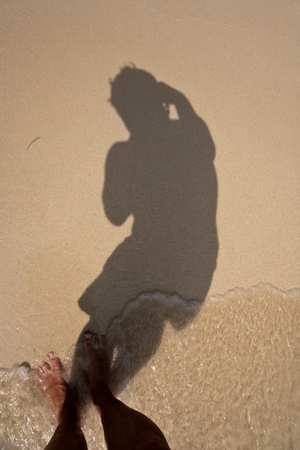 man is throwing shadow to the fine sand of the beach, showing the complete body in a smoth circleの写真素材
