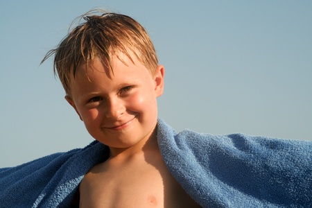 child with towl on the beach is happy and smilesの写真素材