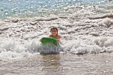 boy has fun with the surfboard at the beachの写真素材