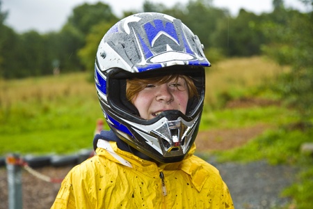 happy boy with helmet at the kart trail in rain with dirty face and clothingの写真素材