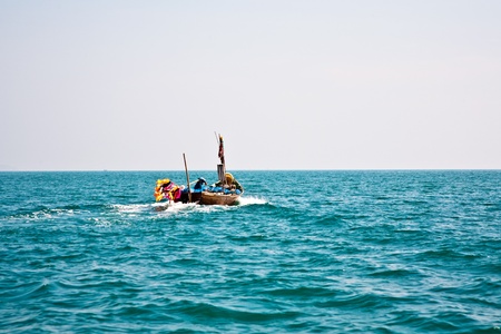 fisherman steers his small wooden boat out to the open sea to go for as catchの写真素材