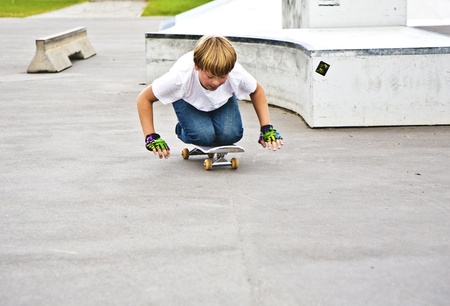 young boy has fun skating on knees with skateboardの写真素材