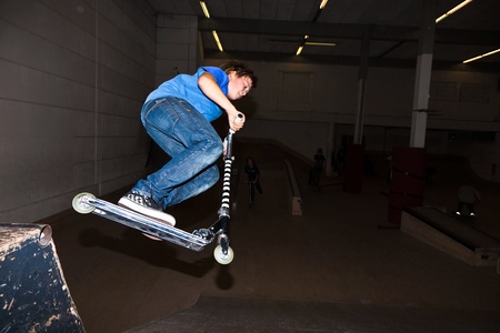 boy with scooter is going airbornein the skate hallの写真素材