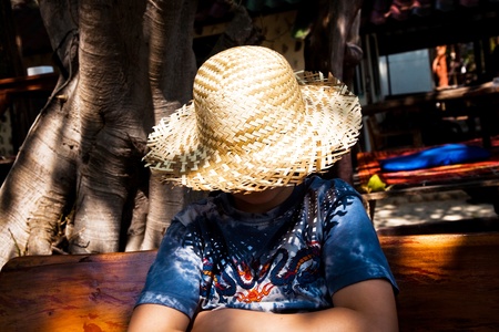 boy is relaxing, smiling and happy and has a rest in the sun at an open air restaurantの写真素材