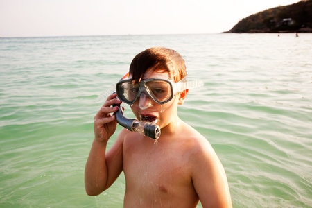young boy is standing in the beautiful clear sea, enjoying the water and starts snorkelingの写真素材