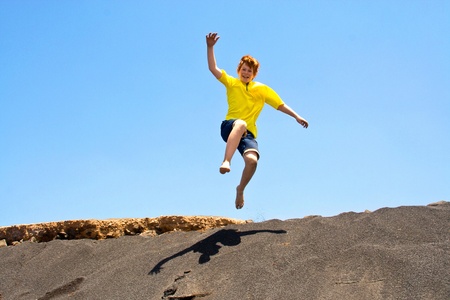 boy has fun jumping in the dunes of the beachin the oceanの写真素材