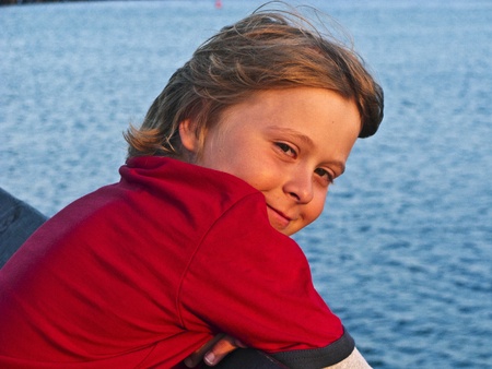 boy stands at the pier and enjoys the seaの写真素材