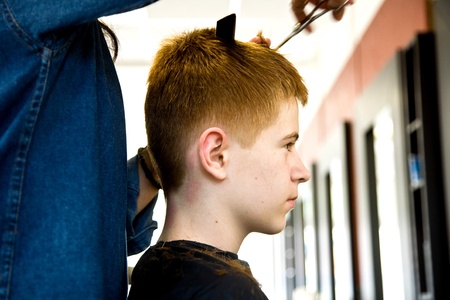 smiling young boy with red hair at the hairdresserの写真素材