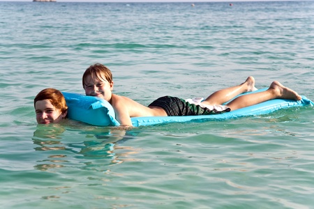 brothers are playing together on a beautiful sea with crystal clear water and blue sky