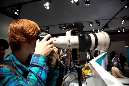 PHOTOKINA, COLOGNE - SEPTEMBER 22: Photokina - World of Imaging, Top Event for the Trade and User, boy tests telelens, September 22, 2010 in Cologne, Germany.のeditorial素材