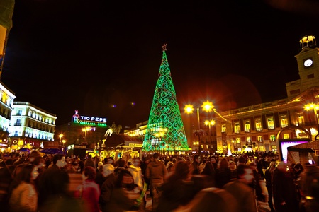 MADRID, SPAIN - DECEMBER 22: People have fun in Christmas time passing the famous illuminated christmas tree at puerta del sol on December 22, 2010 in Madrid, Spain.のeditorial素材