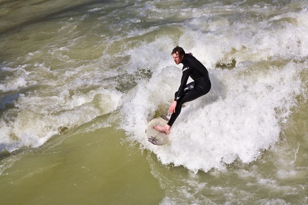 MUENCHEN, GERMANY - APRIL 07: People surfing on the Isar for season opening contest on April 07,2009 Munich. Surfing on the Isar and watching is a famous touristic attraction.の写真素材