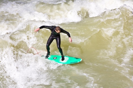 MUENCHEN, GERMANY - APRIL 07: People surfing on the Isar for season opening contest on April 07,2009 Munich. Surfing on the Isar and watching is a famous touristic attraction.のeditorial素材