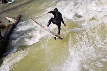 MUENCHEN, GERMANY - APRIL 07: People surfing on the Isar for season opening contest on April 07,2009 Munich. Surfing on the Isar and watching is a famous touristic attraction.のeditorial素材