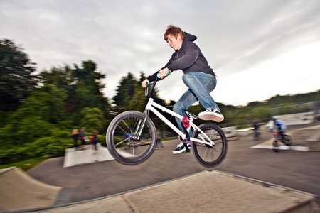 joung red haired boy is jumping with his BMX Bike at the skate park with funの写真素材