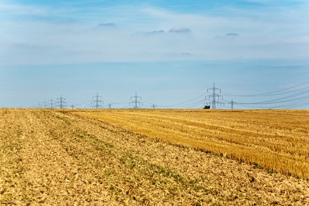tower for electricity in beautiful landscape with golden fieldsの写真素材