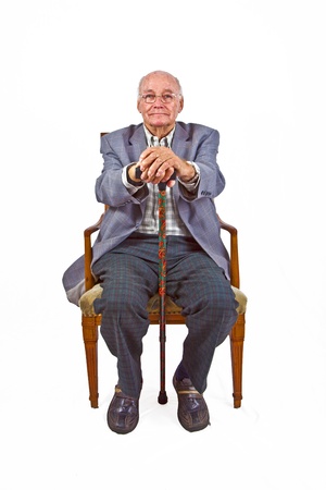 old man sitting in the armchair with his walking stickの写真素材
