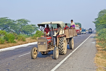 AGRA, INDIA - NOV 16: people in overloaded tractor on the Highway on November 16, 2011 near Agra, India. NH2, a modern divided highway, connects the 200 km distance from Delhi to Agra.のeditorial素材