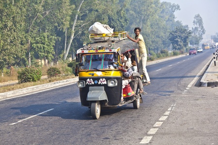 AGRA, INDIA - NOV 16: people in overloaded rickshaws on the Highway on November16, 2011 near Agra, India. NH2, a modern divided highway, connects the 200 km distance from Delhi to Agra.のeditorial素材