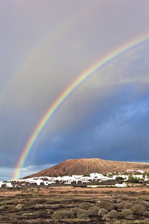 beautiful rainbow over the mountain with dark cloudsの写真素材