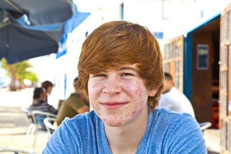 smart boy in puberty sitting on an outdoor table in the village