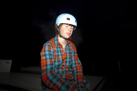 boy with helmet by night at the skate park exhausted by driving bikeの写真素材