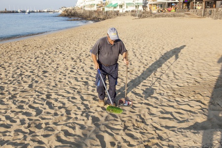 PLAYA BLANCA, SPAIN - APRIL 2: a government man cleans the beach at  April 2,2012 in Playa Blanca, Spain. The beach is artifical and the sand is shipped from Fuerteventura.のeditorial素材